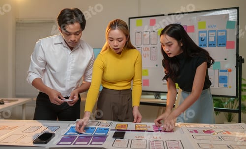 Preview: Asian businessman and businesswoman team working and designing mobile app interface wireframe togeth