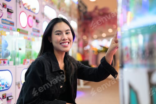 Preview: Happy young woman playing arcade video games indoors