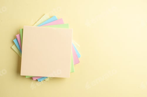 Preview: Above view of stacked sticky note cubes on the right side on shaded yellow background with free