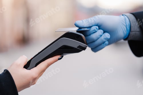 Preview: Cashless payment during quarantine. Hand in rubber gloves, credit card and payment terminal