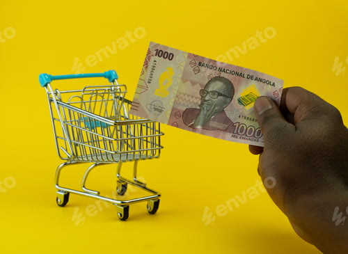 Preview: Male hand holding a banknote of a new serie of angloan money on the background of a little cart