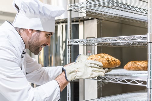 Preview: Side view of chef taking freshly baked bread from shelf