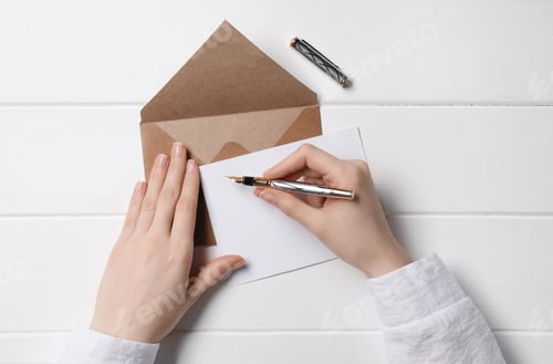 Preview: Woman writing letter at white wooden table, top view