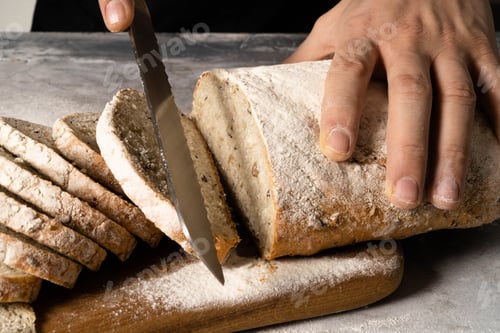 Preview: Male hands spread butter on a slice of bread.
