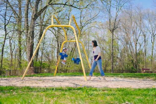 Preview: Mother and diverse toddler girl bonding together as a family on a nice summer day at playground park