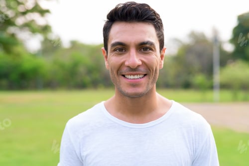 Preview: Face of happy young handsome Hispanic man smiling at the park