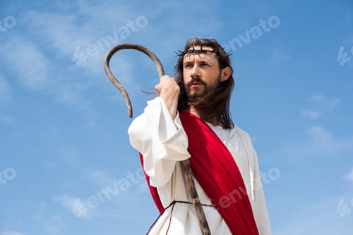Preview: Jesus in robe, red sash and crown of thorns standing with wooden staff against blue sky and looking