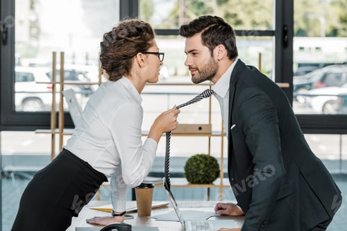 Preview: side view of businessman and businesswoman flirting at workplace in office