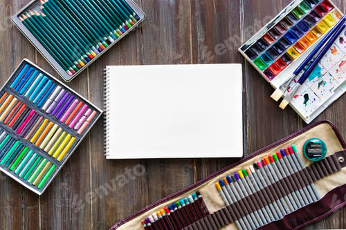 Preview: art workplace, pencils, brushes, watercolor paints and crayon pastel chalks Flat lay on wooden table