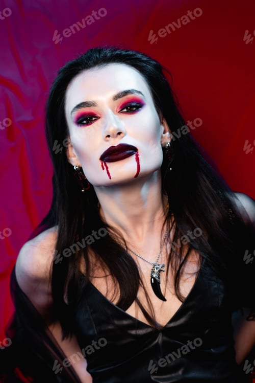 Preview: pale woman with blood on face looking at camera on red