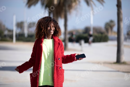 Preview: woman jumping and dancing while listening music and smiling outside