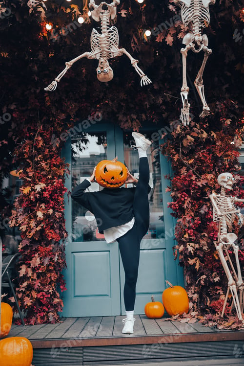 Preview: Girl with a pumpkin head posing at the door on the street