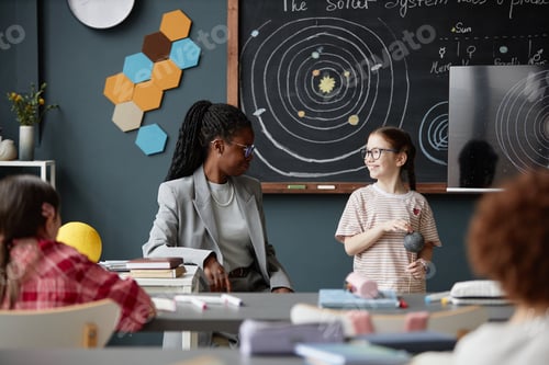 Preview: Caucasian Girl Explaining Solar System Model to Black Woman Teacher in Classroom