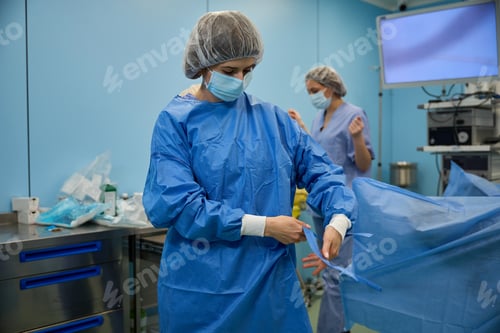 Preview: Young female surgeon getting ready to operate in hospital