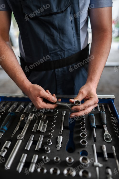 Preview: Mechanic choosing right tool for repairing car in workshop