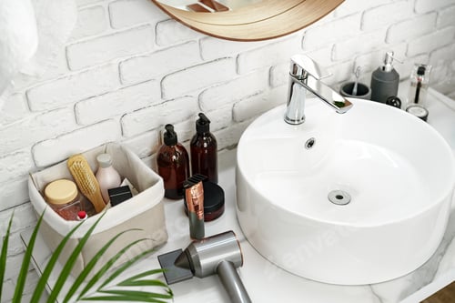 Preview: A modern hairdryer placed on a bathroom countertop surrounded by beauty products and a green plant