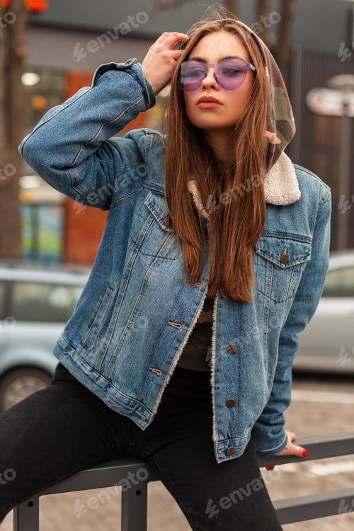 Preview: Pretty attractive woman with hood in stylish blue denim jacket on the street. American girl