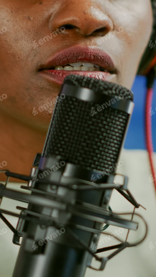 Preview: Close up of african influencer answering questions while talking into microphone
