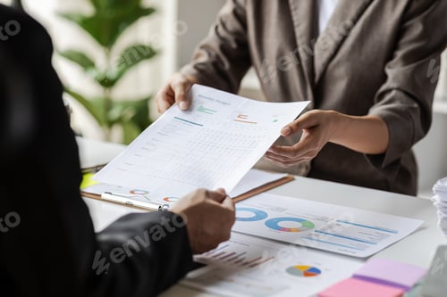 Preview: Coworkers are discussing company growth charts and graphs during a budget meeting.