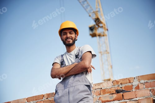 Preview: Standing with arms crossed. Handsome Indian man is on the construction site