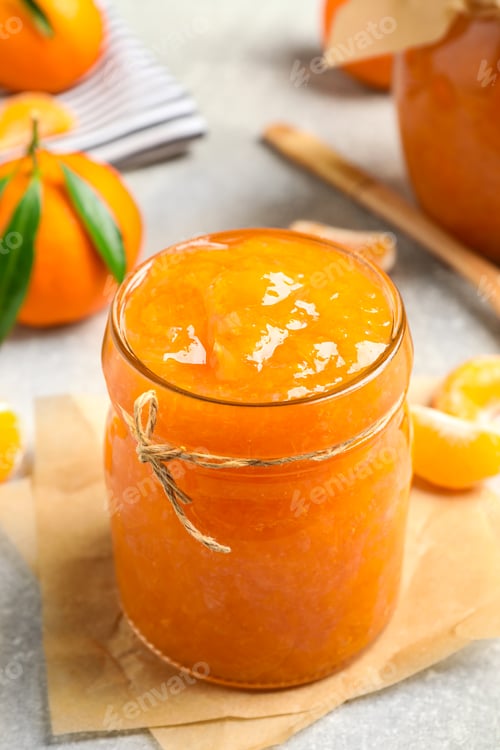 Preview: Delicious tangerine jam on light grey table, closeup