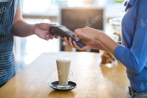 Preview: Mid-Section Of Customer Making Payment Through Payment Terminal At Counter In Caf\X92\Xa9