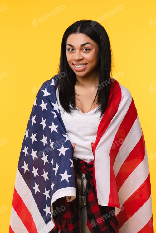 Preview: Vertical shot of Afro-american woman wrapped covering the American flag standing isolated