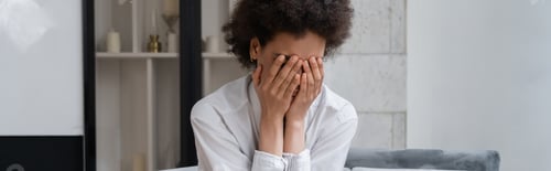Preview: stressed african american woman in white shirt covering face in living room, banner
