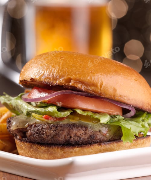 Preview: gourmet cheeseburger with mug of beer in background