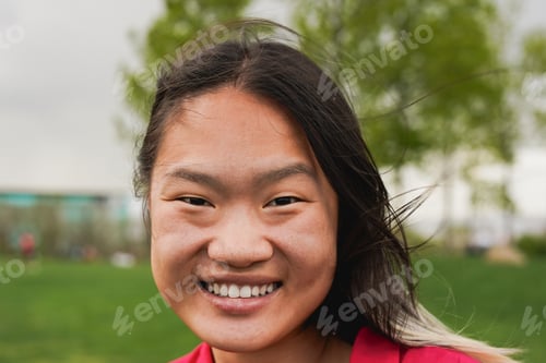 Preview: Happy young asian girl smiling on camera at city park during spring season - Chinese woman portrait