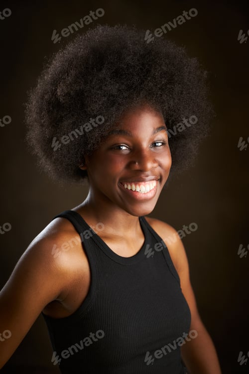 Preview: young African American woman in black t-shirt with afro hairstyle smiling and looking at the camera