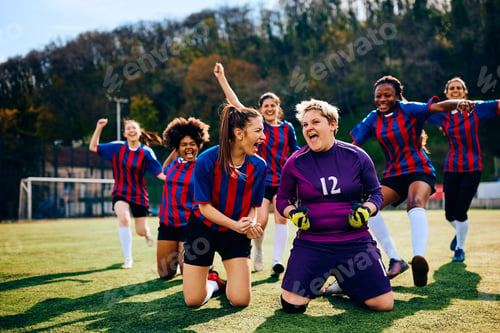 Preview: Cheerful women's soccer team screaming while celebrating victory on playing field.