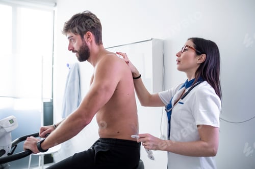 Preview: Man on Exercise Bike Receiving Medical Examination