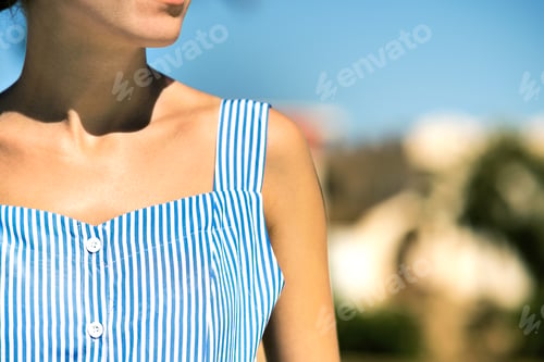 Preview: Close up of young woman in blue summer dress outdoors.