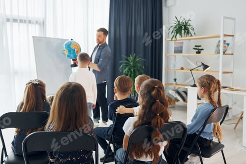 Preview: Geography lesson. With globe in hands. Group of children students in class at school with teacher
