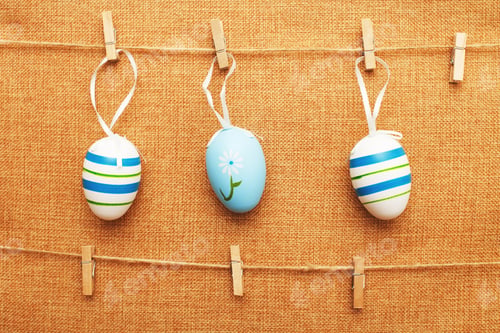 Preview: easter colorful eggs hanging on clothespins on textile background