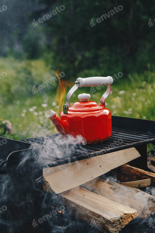 Preview: Heating up water on a red kettle while camping on a campfire
