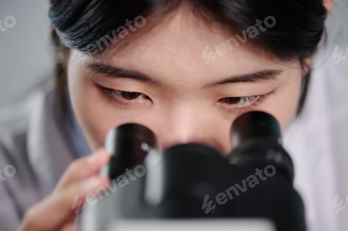 Preview: Female scientist looking in microscope