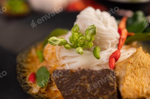 Preview: Chicken curry in a black cup with rice noodles.