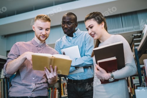 Preview: Attentive multiracial students with books looking at open book