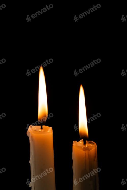 Preview: Two lit white candles with copy space on black background