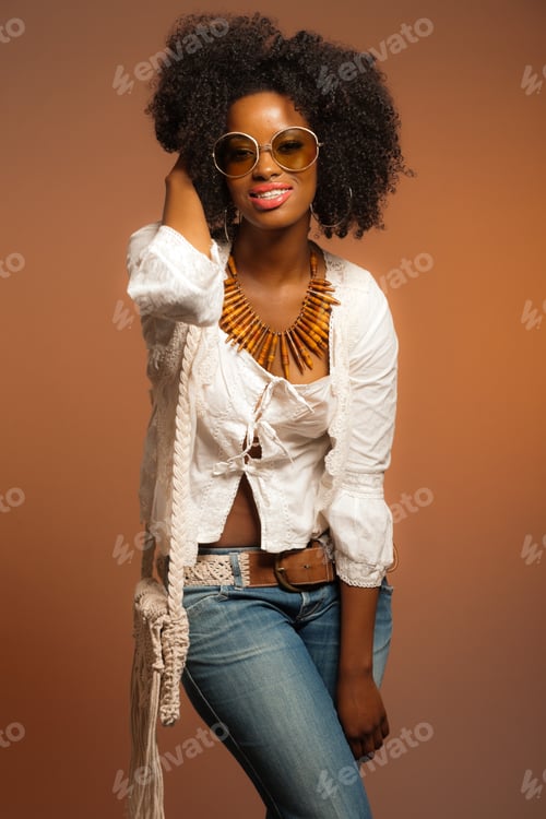 Preview: Vintage 70S Fashion Black Woman With Sunglasses. White Shirt And Jeans Against Brown Background.