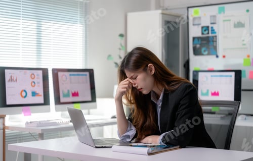 Preview: Stressed businesswoman having headache while working with laptop in office