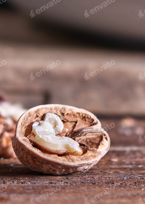 Preview: Closeup of a half of walnut on a wooden kitchen table with copy space. Vegetarian product