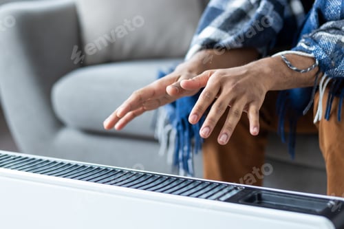 Preview: Man hands close up near a heating device. Man tries to warm himself while sitting at home on a sofa