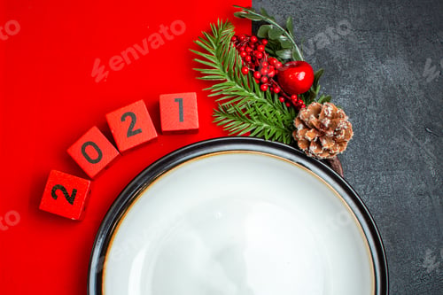 Preview: New year background with dinner plate decoration accessories fir branches and numbers on a red