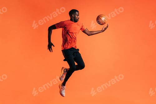 Preview: Side view of young male jumping and throwing up a basket ball in studio