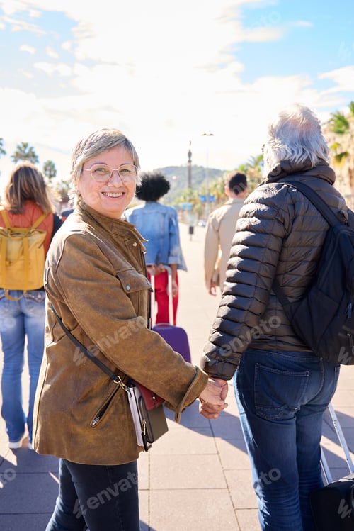 Preview: Vertical. Happy senior Caucasian couple walking of street European city on holidays holding hands