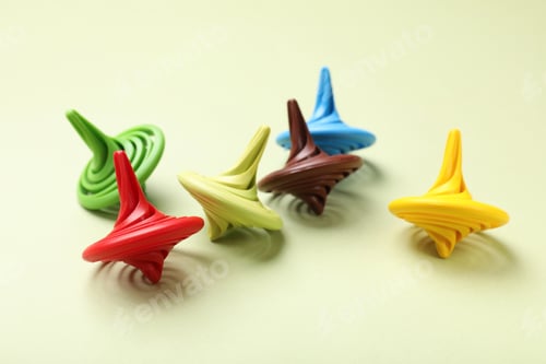 Preview: Many colorful spinning tops on green background, closeup