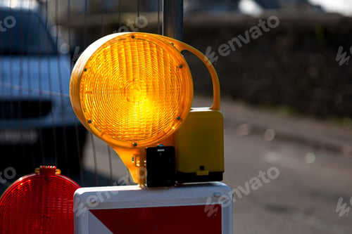 Preview: Close-up of yellow and red warning lights with street barriers
